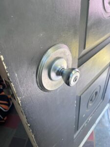 A close-up of a silver door knob with a keyhole on a slightly open black wooden door, perfect for any local locksmith seeking detail or inspiration.