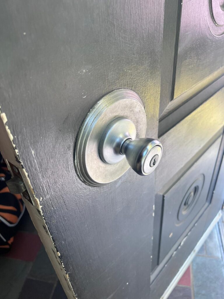 A close-up of a silver door knob with a keyhole on a slightly open black wooden door, perfect for any local locksmith seeking detail or inspiration.