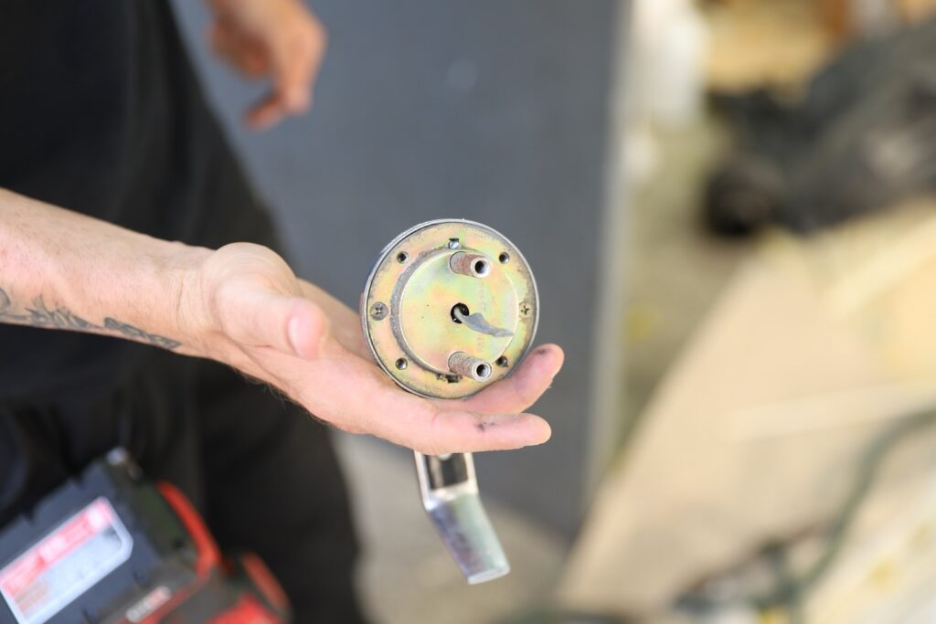 A local locksmith in New Jersey holds a round metallic component with three protruding tubes and a lever, showing it to the camera.