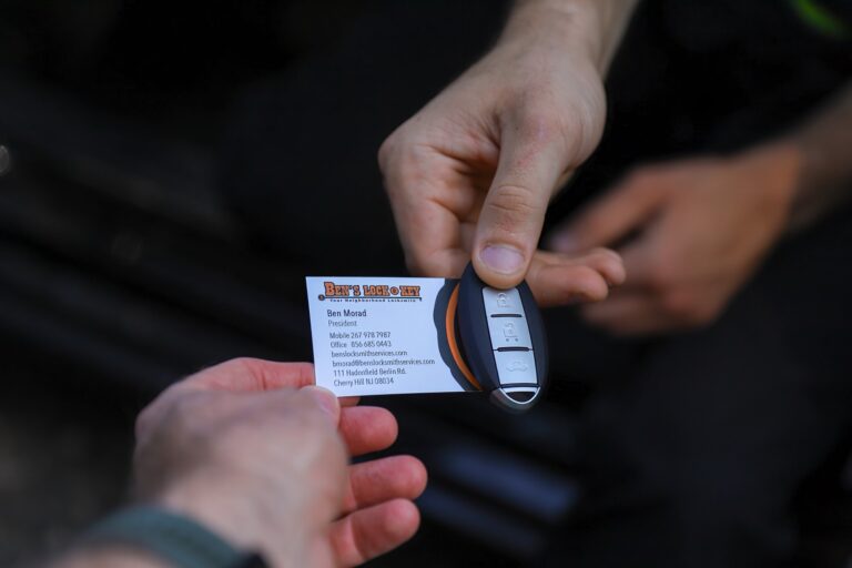 A person hands a business card and a car key to another person, both shown from the wrist down—capturing a quick exchange that could happen anywhere, even in New Jersey.