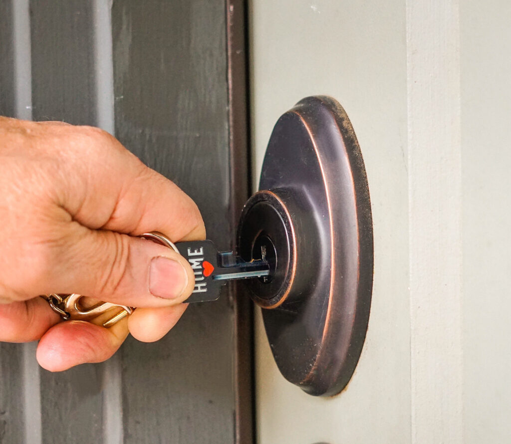 A hand is inserting a key labeled HOME into the keyhole of a front door lock, showcasing the expertise of a local New Jersey locksmith.