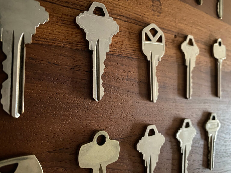 Close-up of various metal keys arranged in rows on a wooden surface, perfect for a New Jersey locksmith shop near me.